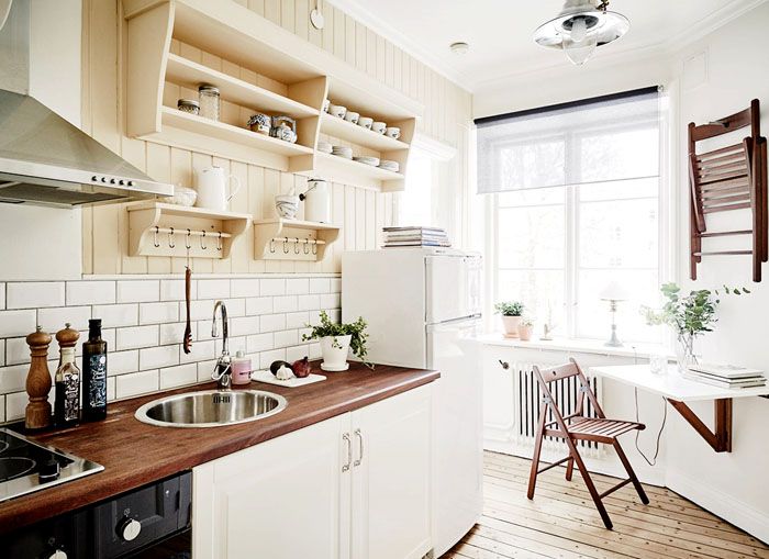 A small folding table on the wall of a narrow kitchen
